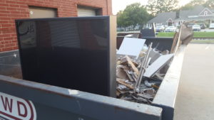 large flat screen TV in trash dumpster